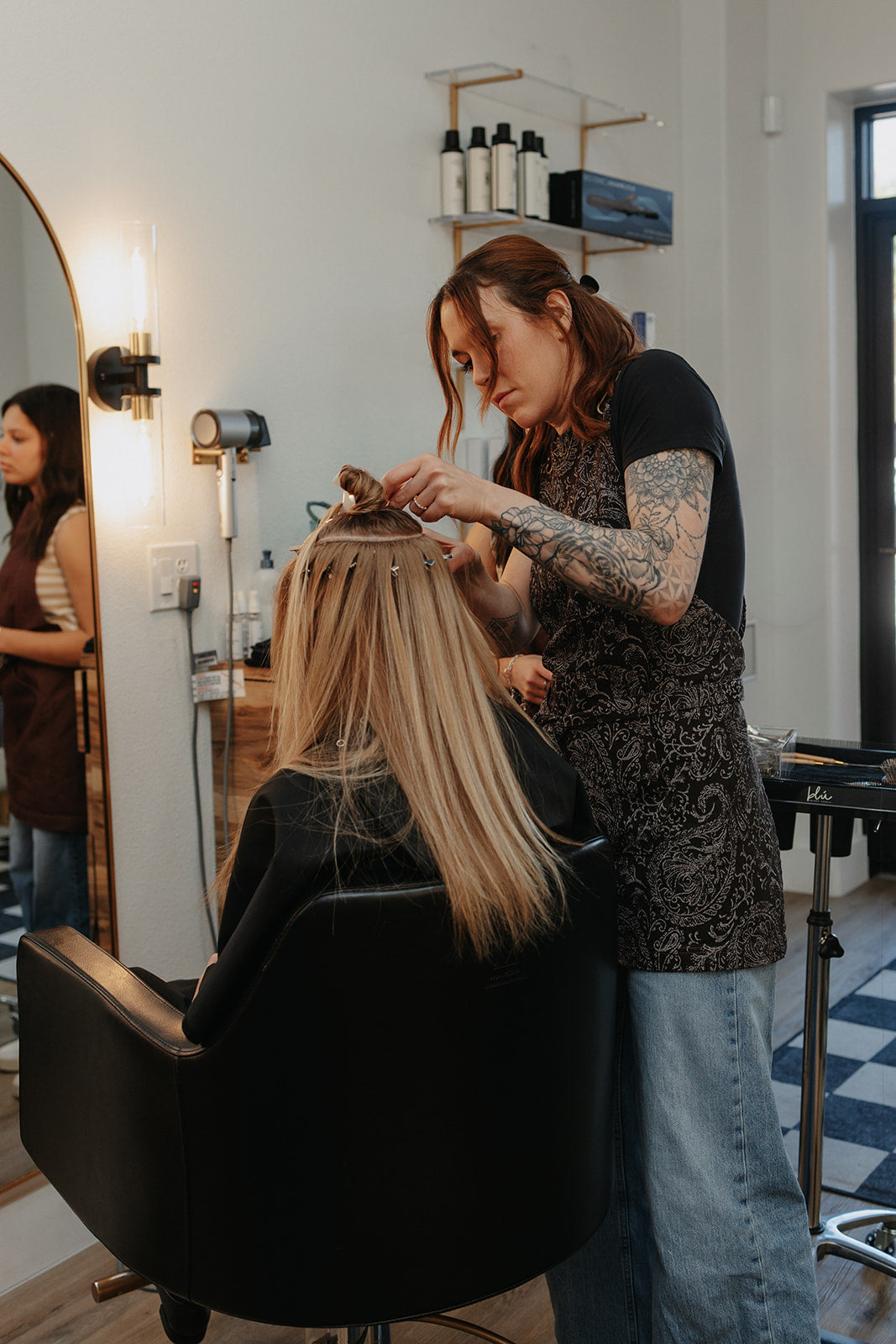 Hair stylist working while wearing The Outlaw cross-back salon apron by J Clark Designed
