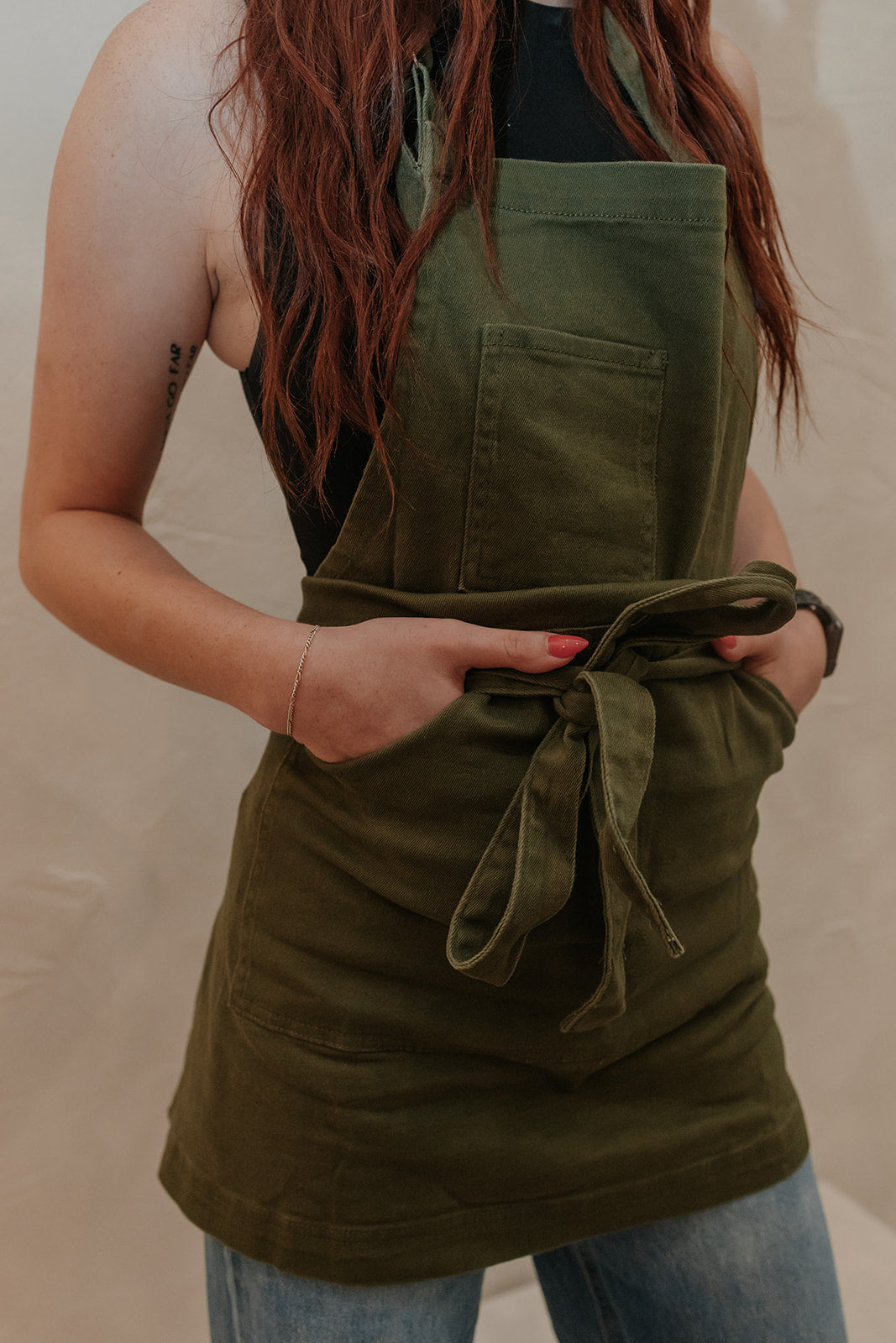 Petite hair stylist wearing olive green apron by J Clark Designed