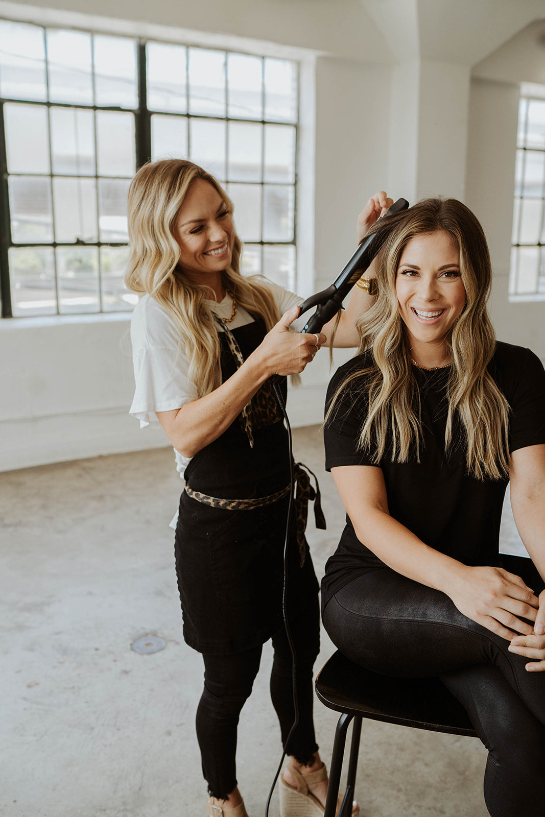 Hair stylist wearing leopard apron while curling hair
