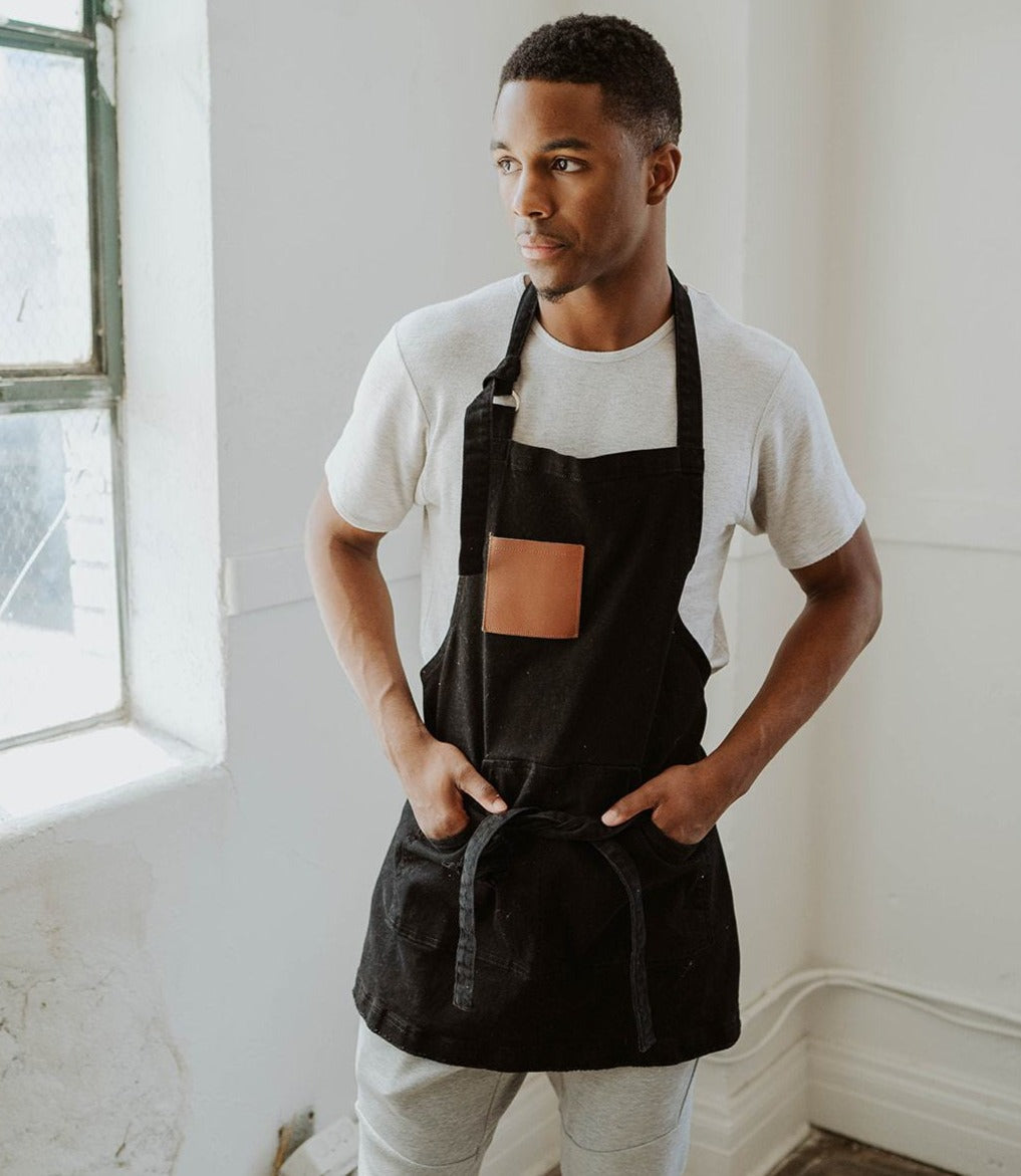 Model wearing black and leather apron