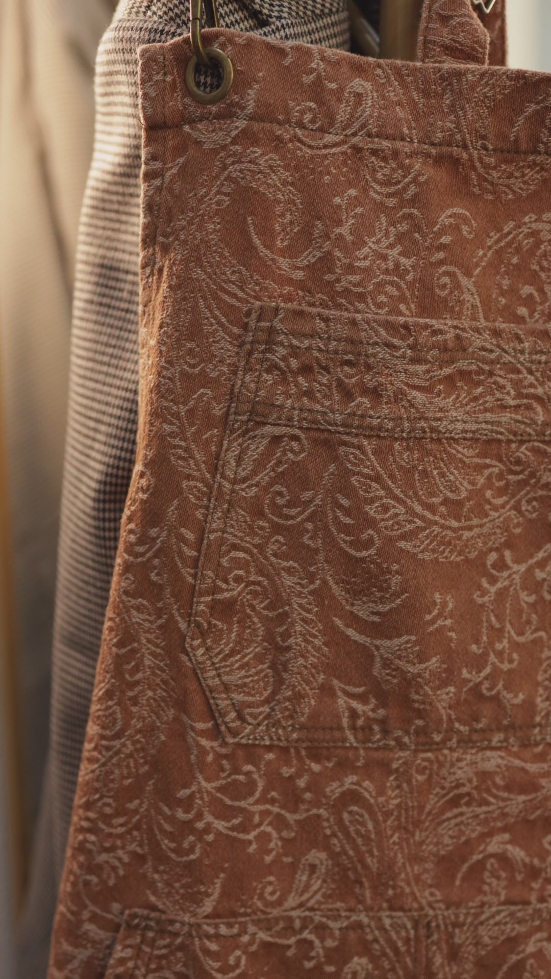 Short video clip of the Bohemian cross-back denim apron by J Clark Designed that shows close-up detail of the paisley fabric pattern and pockets.