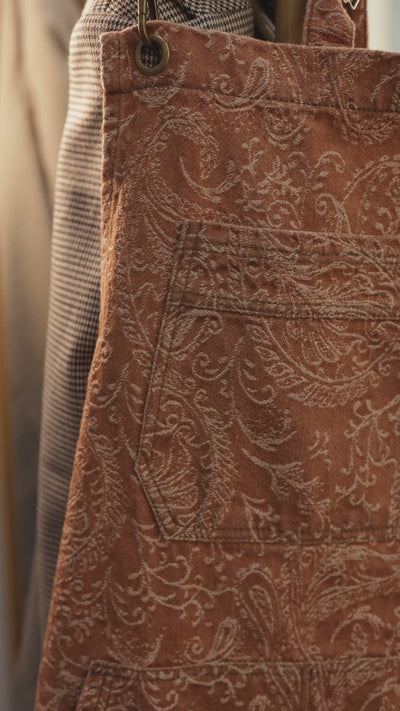 Short video clip of the Bohemian cross-back denim apron by J Clark Designed that shows close-up detail of the paisley fabric pattern and pockets.