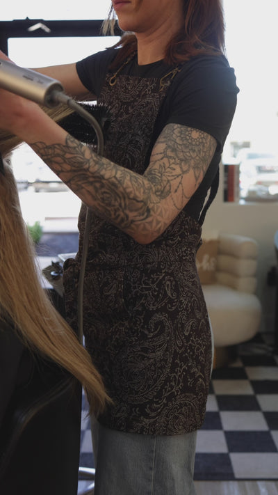 Short video clip of a hair stylist working while wearing the Outlaw cross-back salon apron by J Clark Designed